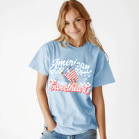 Thumbnail for A women with strawberry blonde hair wearing a light blue t shirt that says 